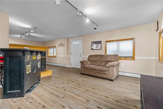 living room featuring a baseboard radiator, track lighting, and light wood-type flooring