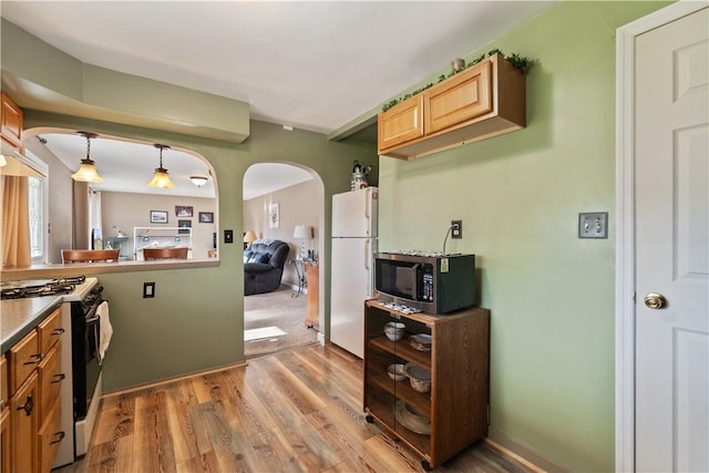 kitchen featuring hardwood / wood-style flooring, decorative light fixtures, and white appliances