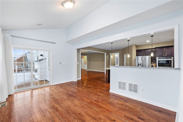 interior space with light stone countertops, appliances with stainless steel finishes, dark brown cabinetry, dark wood-type flooring, and lofted ceiling