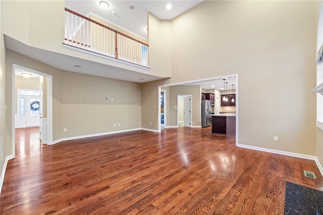 unfurnished living room featuring dark hardwood / wood-style floors and a high ceiling