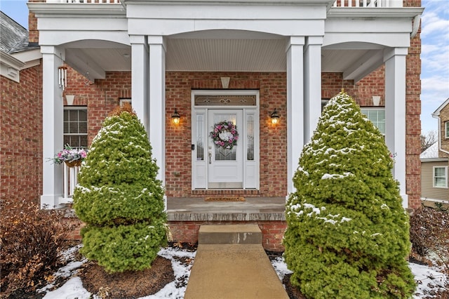 snow covered property entrance featuring covered porch