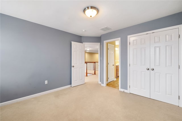 unfurnished bedroom with light colored carpet and a closet