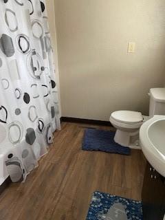 bathroom with hardwood / wood-style flooring, a shower with curtain, toilet, and sink