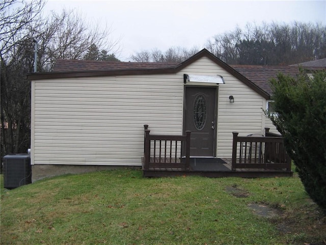 view of front facade featuring cooling unit, a wooden deck, and a front lawn