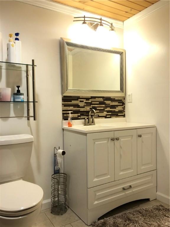 bathroom featuring vanity, wooden ceiling, crown molding, tile patterned flooring, and decorative backsplash