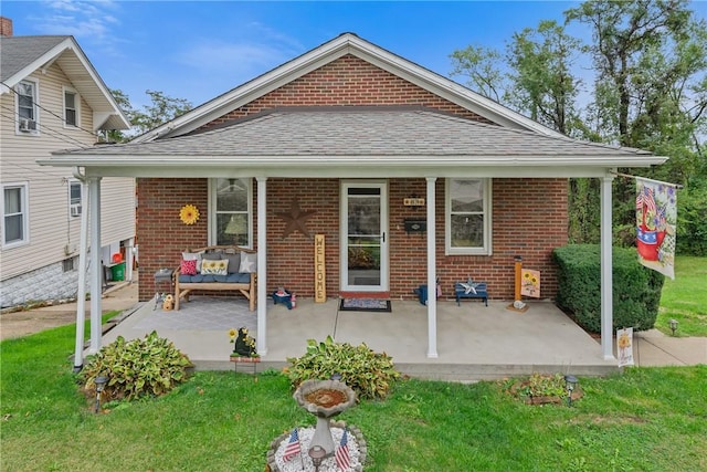 back of property with a lawn and a porch