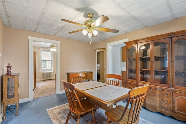 carpeted dining space with radiator heating unit and ceiling fan