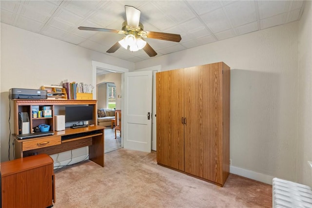 carpeted office with radiator heating unit and ceiling fan