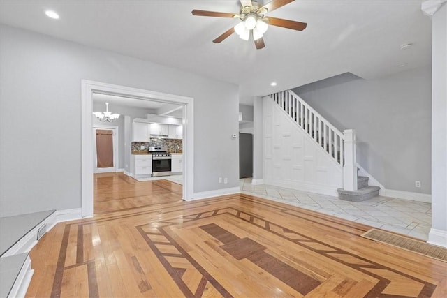 unfurnished living room with ceiling fan with notable chandelier