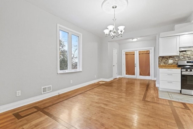 unfurnished dining area with light hardwood / wood-style floors and an inviting chandelier