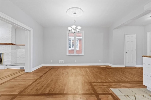 unfurnished dining area featuring a chandelier, light hardwood / wood-style flooring, and a fireplace