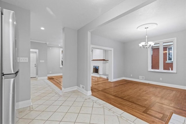 interior space featuring an inviting chandelier, a brick fireplace, and light tile patterned flooring