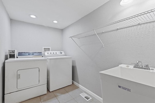 laundry room with light tile patterned floors, washer and clothes dryer, and sink