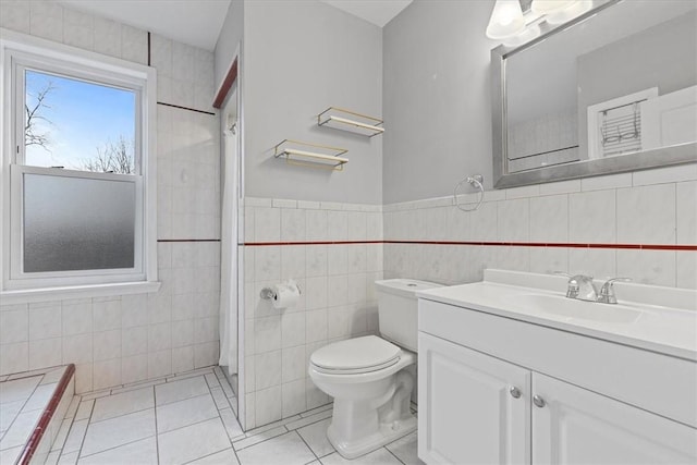 bathroom featuring toilet, vanity, tile patterned floors, and tile walls