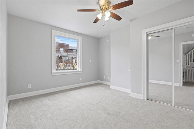 unfurnished bedroom with ceiling fan, a closet, and light carpet