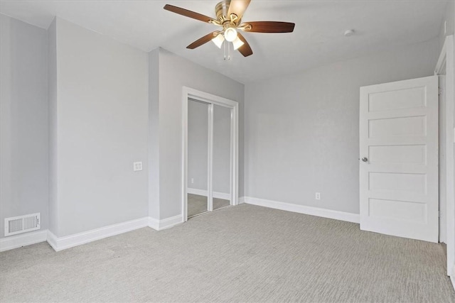 unfurnished bedroom featuring ceiling fan, light carpet, and a closet