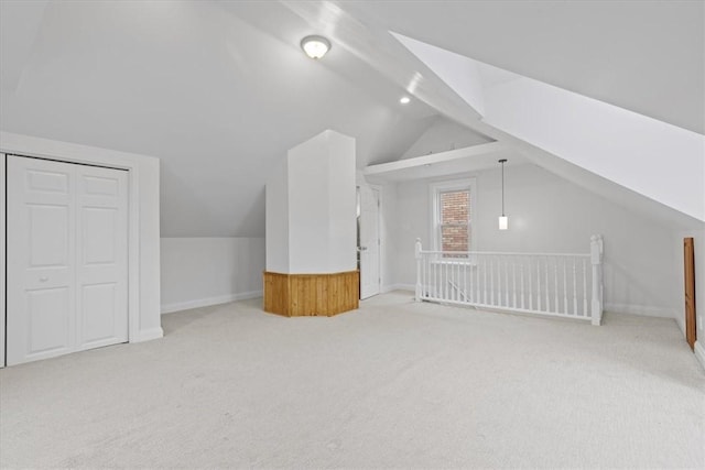 additional living space featuring light colored carpet and vaulted ceiling