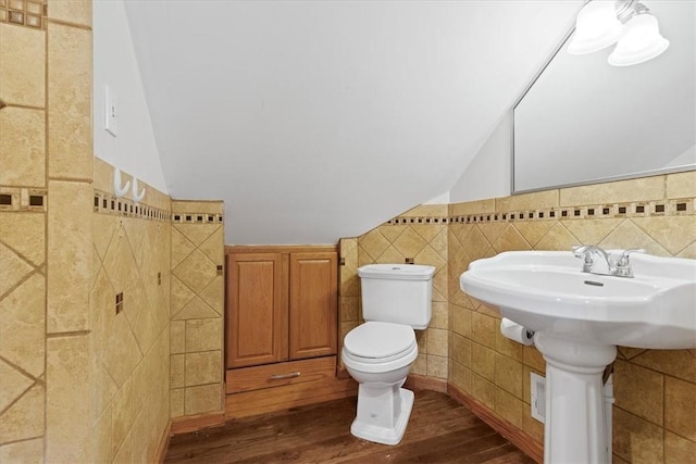 bathroom featuring wood-type flooring, toilet, lofted ceiling, and tile walls