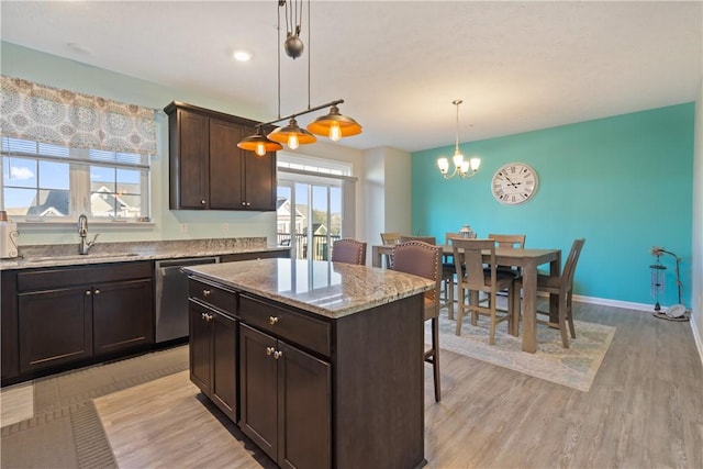 kitchen featuring a center island, sink, stainless steel dishwasher, decorative light fixtures, and dark brown cabinetry