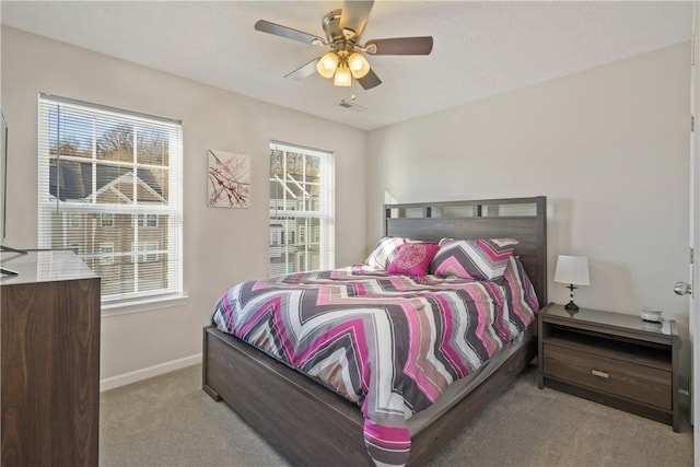 bedroom with ceiling fan, light carpet, and multiple windows