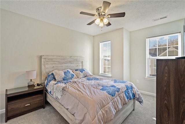 carpeted bedroom with ceiling fan and a textured ceiling