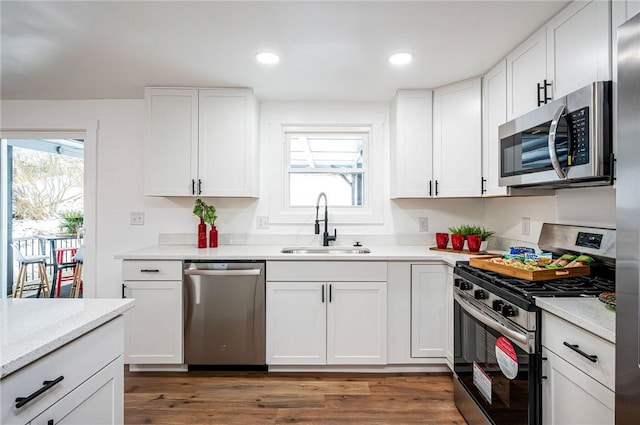 kitchen with dark hardwood / wood-style flooring, white cabinetry, sink, and stainless steel appliances