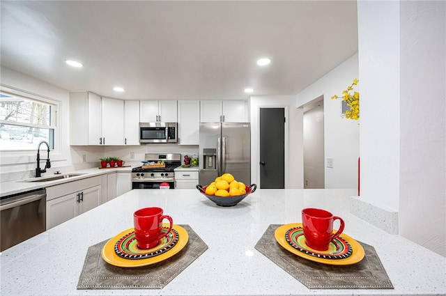 kitchen featuring light stone counters, white cabinetry, sink, and appliances with stainless steel finishes