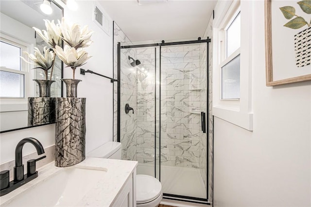 bathroom featuring a shower with door, vanity, and toilet