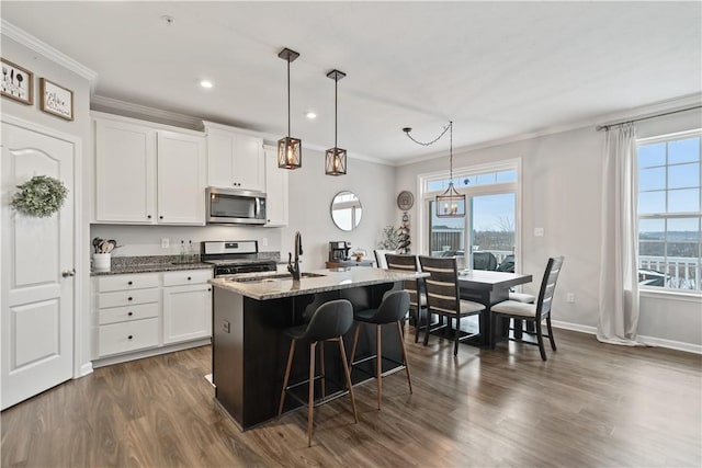 kitchen with white cabinetry, a kitchen breakfast bar, dark stone countertops, an island with sink, and pendant lighting