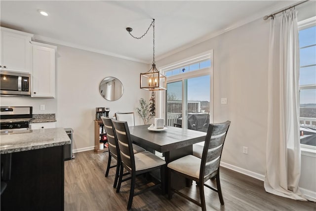 dining space featuring dark hardwood / wood-style floors, ornamental molding, and a notable chandelier