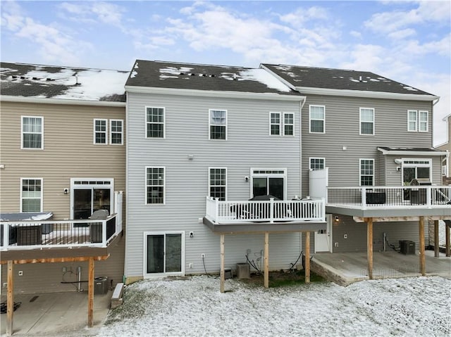 snow covered back of property featuring central AC unit