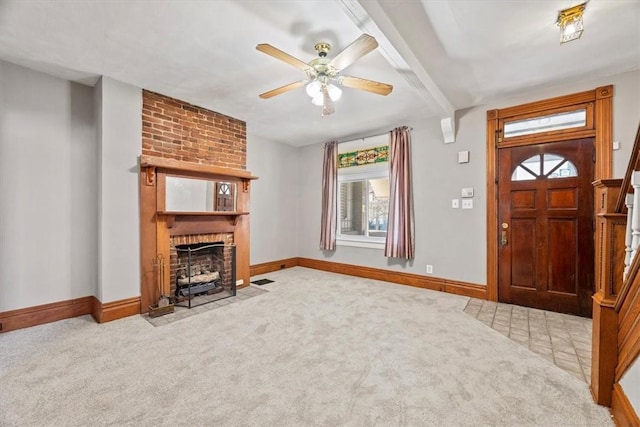 carpeted entryway featuring beamed ceiling, ceiling fan, and a brick fireplace