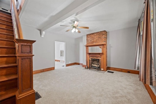 unfurnished living room featuring light carpet, beam ceiling, a brick fireplace, and ceiling fan