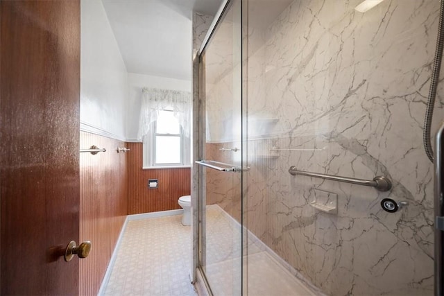 bathroom featuring wooden walls, toilet, and a shower with shower door