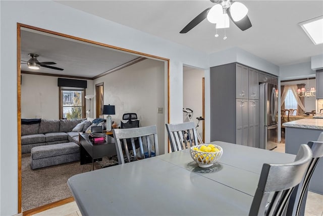 dining area featuring light carpet, ceiling fan with notable chandelier, and crown molding