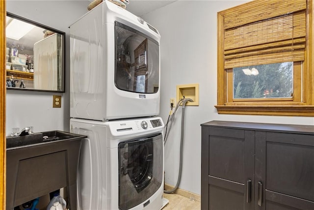 laundry room featuring cabinets and stacked washer / dryer