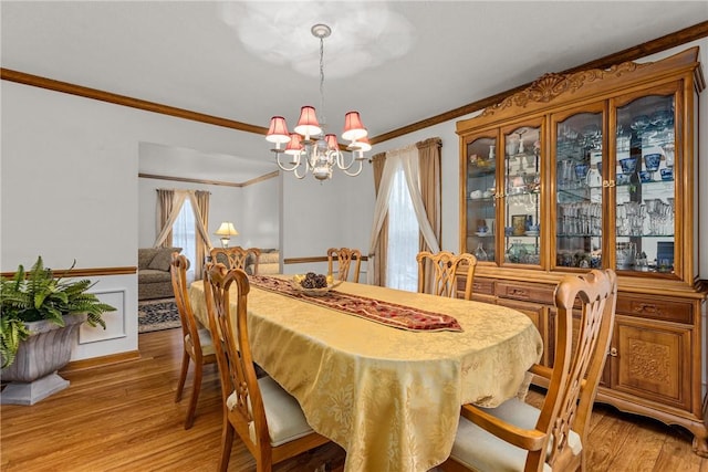 dining area with light hardwood / wood-style floors, crown molding, and an inviting chandelier