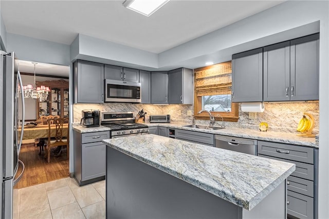 kitchen featuring sink, a center island, gray cabinets, light tile patterned flooring, and appliances with stainless steel finishes