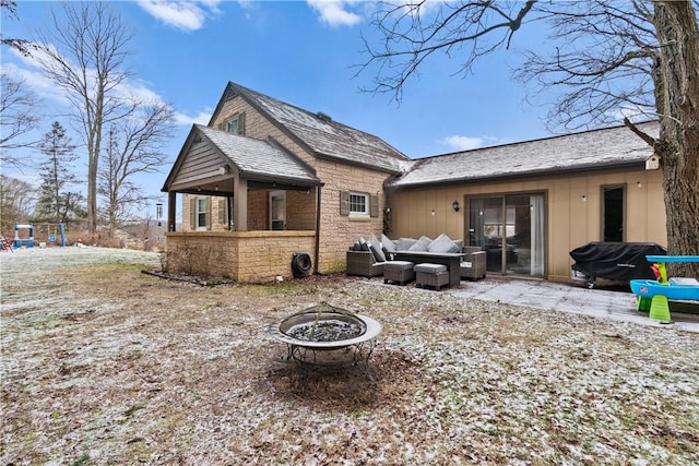 rear view of property featuring an outdoor living space with a fire pit