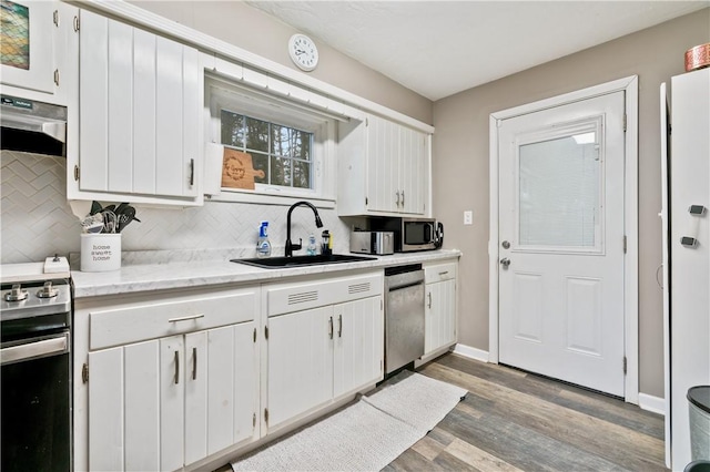 kitchen with tasteful backsplash, sink, white cabinets, and appliances with stainless steel finishes