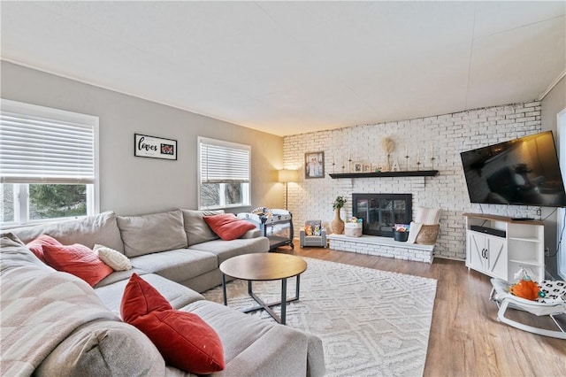 living room featuring hardwood / wood-style floors, plenty of natural light, brick wall, and a brick fireplace