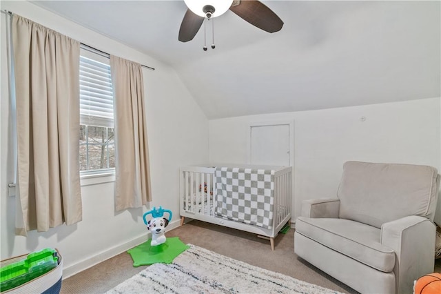 carpeted bedroom with ceiling fan, a crib, multiple windows, and vaulted ceiling