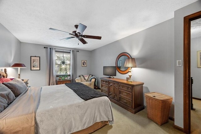 carpeted bedroom with ceiling fan and a textured ceiling