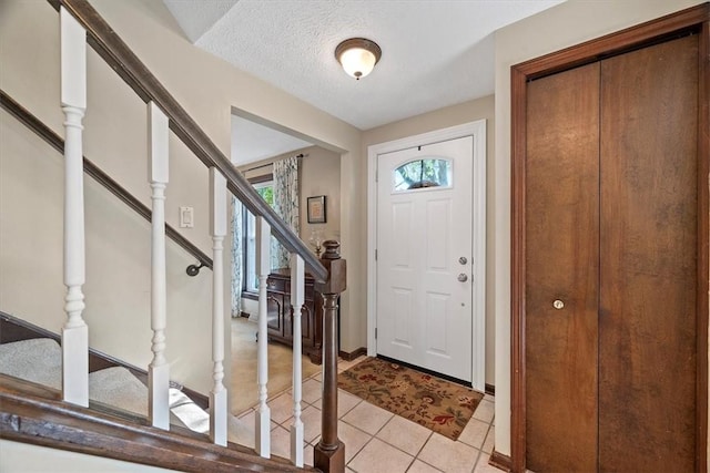 foyer entrance with light tile patterned floors and a textured ceiling