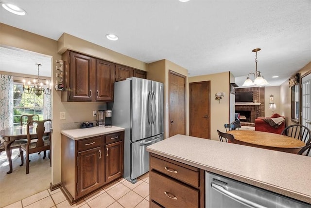 kitchen with appliances with stainless steel finishes, decorative light fixtures, a notable chandelier, a fireplace, and light tile patterned flooring