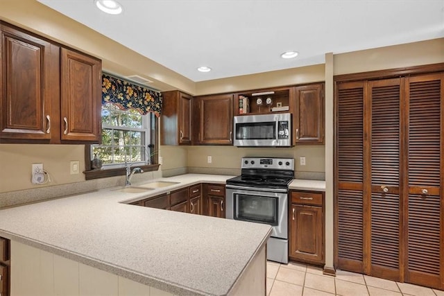 kitchen with kitchen peninsula, sink, light tile patterned floors, and appliances with stainless steel finishes