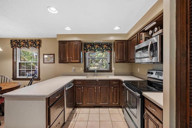 kitchen featuring dark brown cabinetry, sink, stainless steel appliances, kitchen peninsula, and light tile patterned flooring