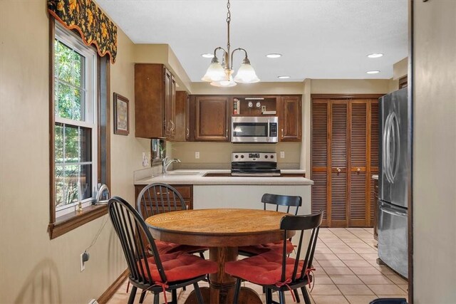 kitchen featuring sink, hanging light fixtures, light tile patterned floors, stainless steel appliances, and a chandelier