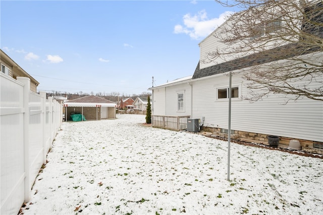 yard layered in snow featuring central AC unit and a carport