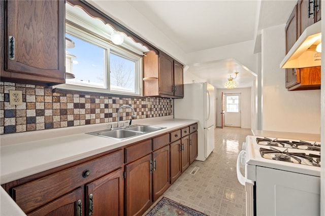 kitchen featuring decorative backsplash, sink, and white appliances